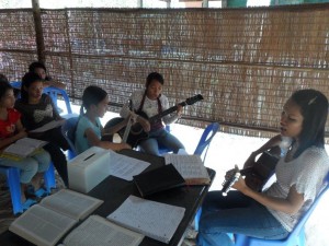 Darlin, Srey Nich and Sokha playing the guitar and singing during Sunday worship