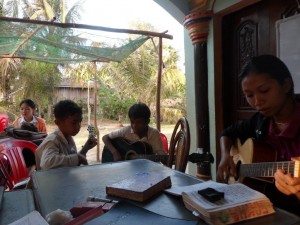 Pisey, Bolong, and Veasna playing the guitar before the to start an English Outreach class